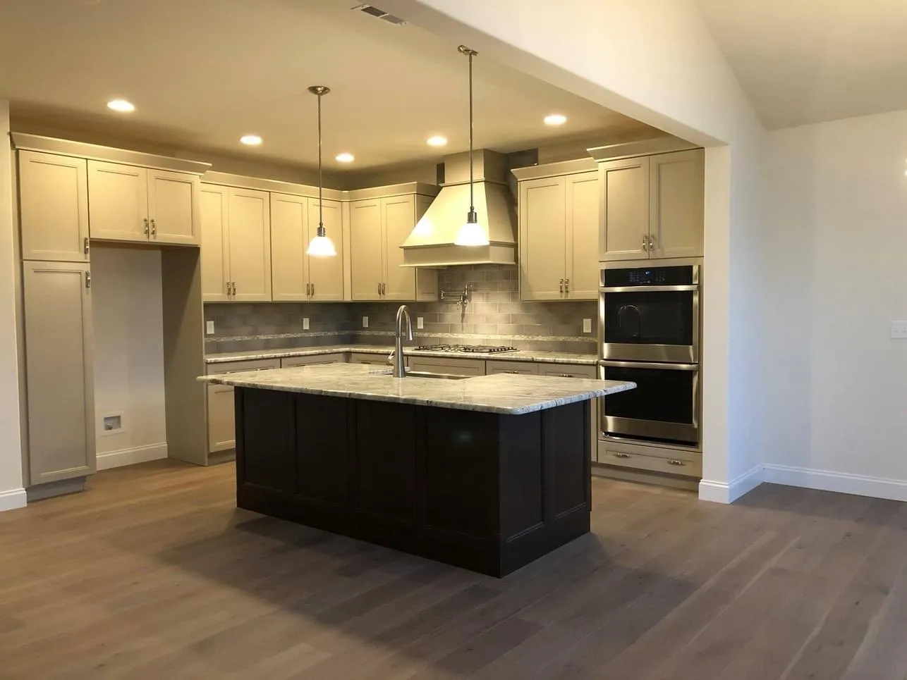 A kitchen featuring beige perimeter cabinets and a dark brown kitchen island with stone countertops.