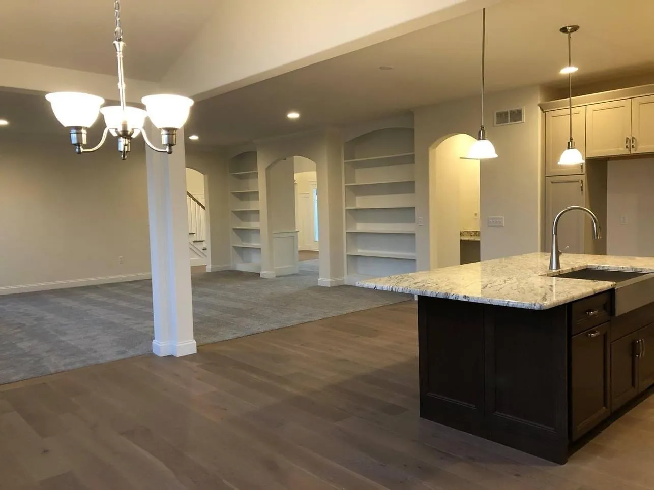 Built-in shelving units with arched tops flank the entrance to a carpeted living area.