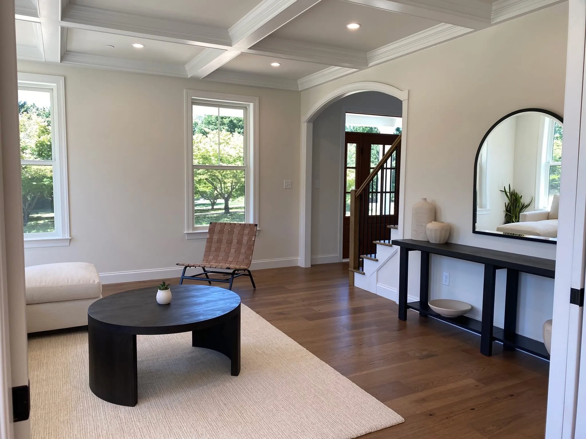 A coffered ceiling and arched doorway transition into a living room with hardwood floors.