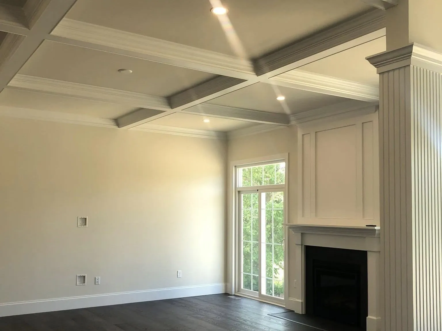 A living room features a coffered ceiling, a white fireplace mantel, and fluted column trim.