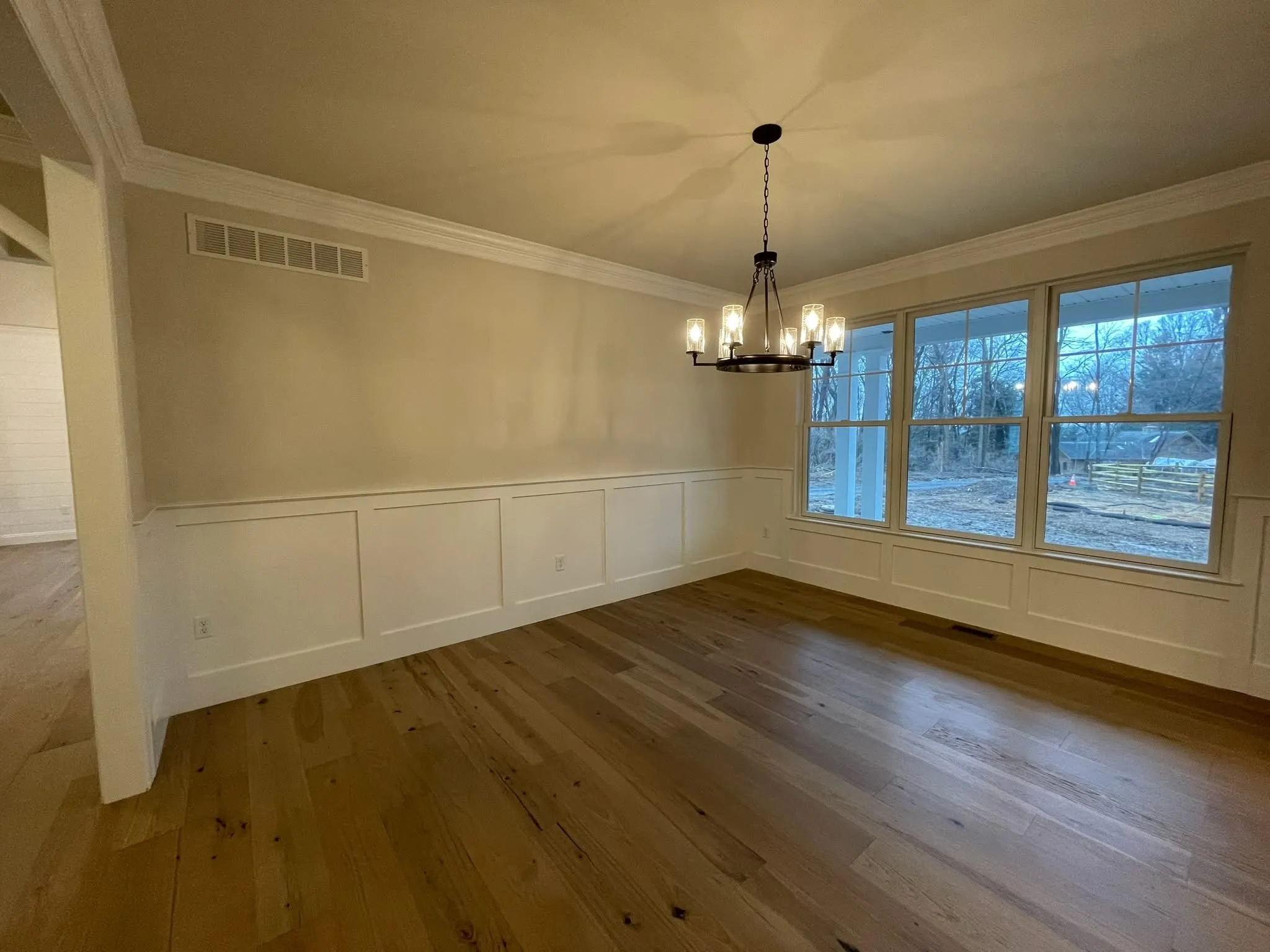 White wainscoting paneling installed on the lower walls of a dining room with hardwood floors.