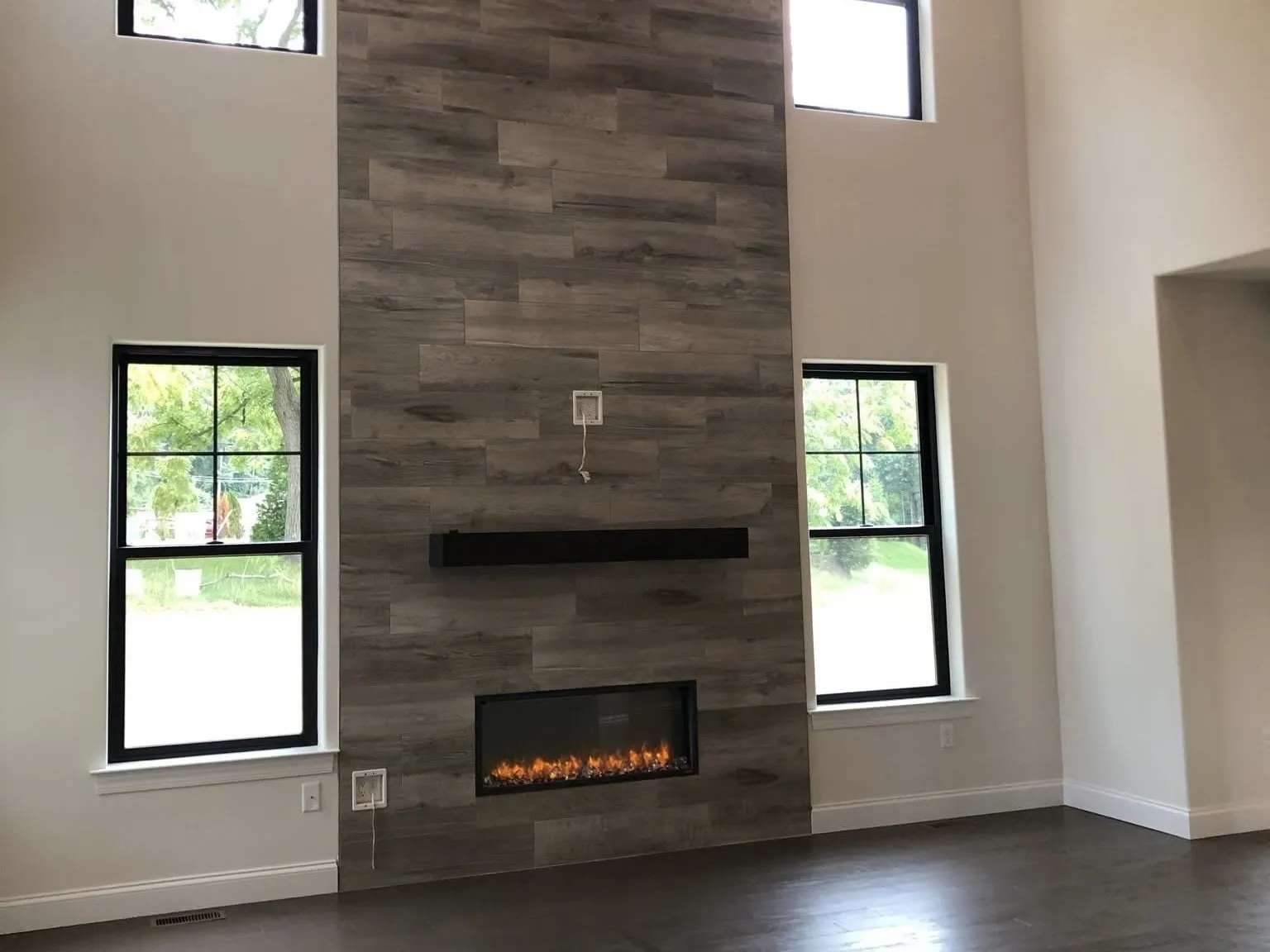 A modern linear fireplace surrounded by floor to ceiling gray wood planks in a living room.