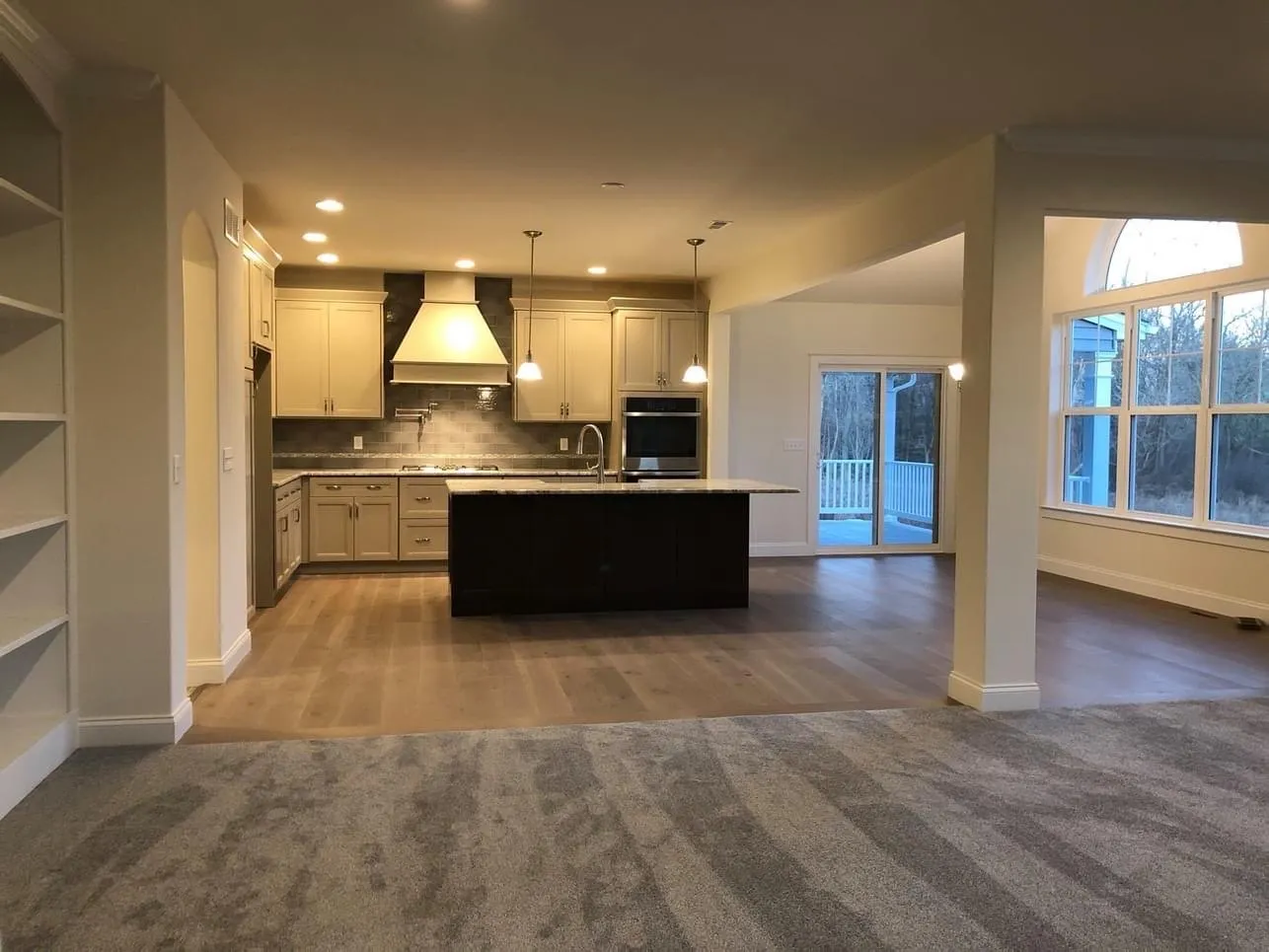 A kitchen featuring light cabinets, a dark island, and built-in shelving in an open floor plan.