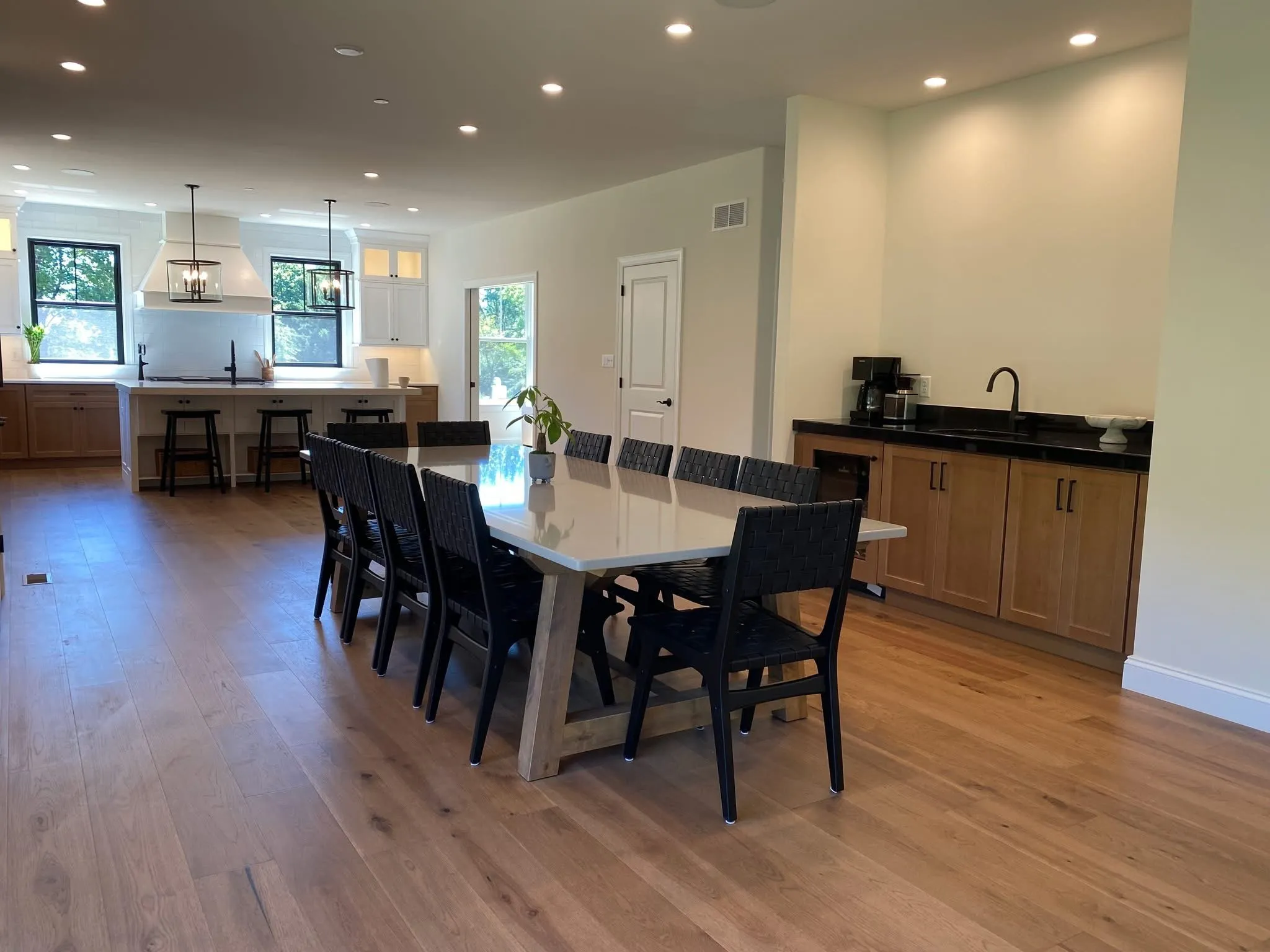 A modern kitchen and dining area featuring wood cabinetry and a black wet bar.