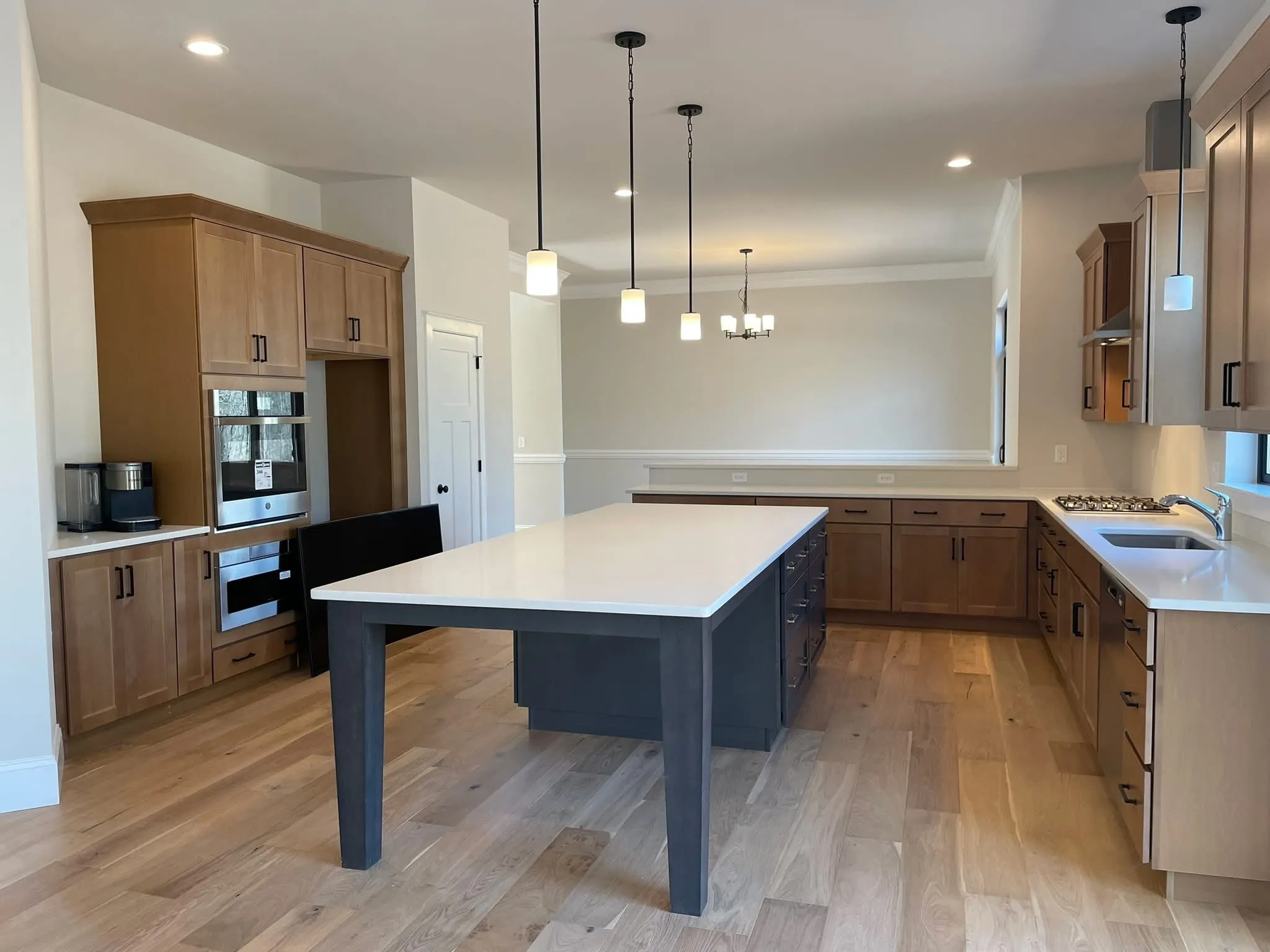Natural wood kitchen cabinets with a dark gray island and white quartz countertops in a new home.