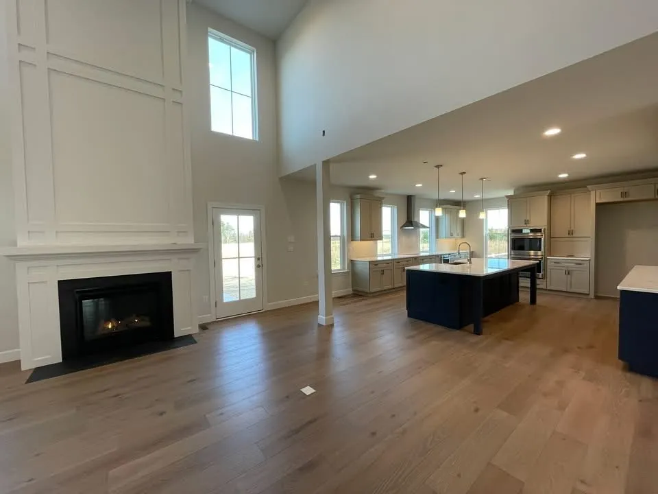 A two-story board and batten fireplace surround next to a kitchen with a navy island.