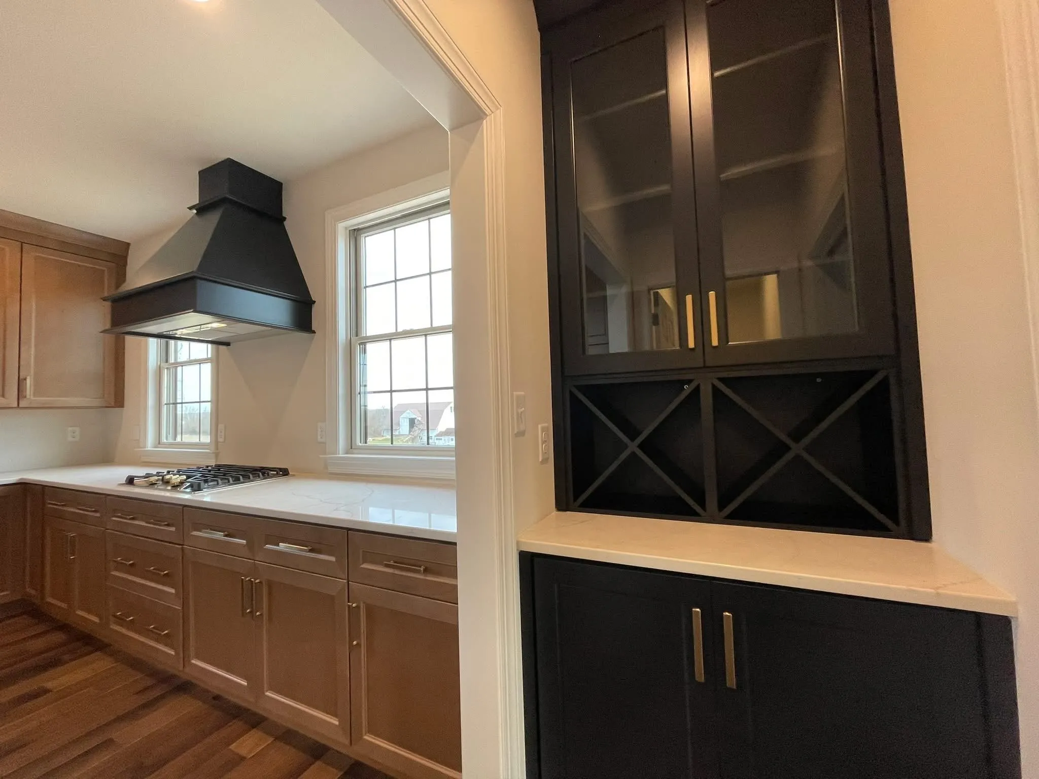 A kitchen featuring light wood lower cabinets and a black built-in cabinet with wine storage.