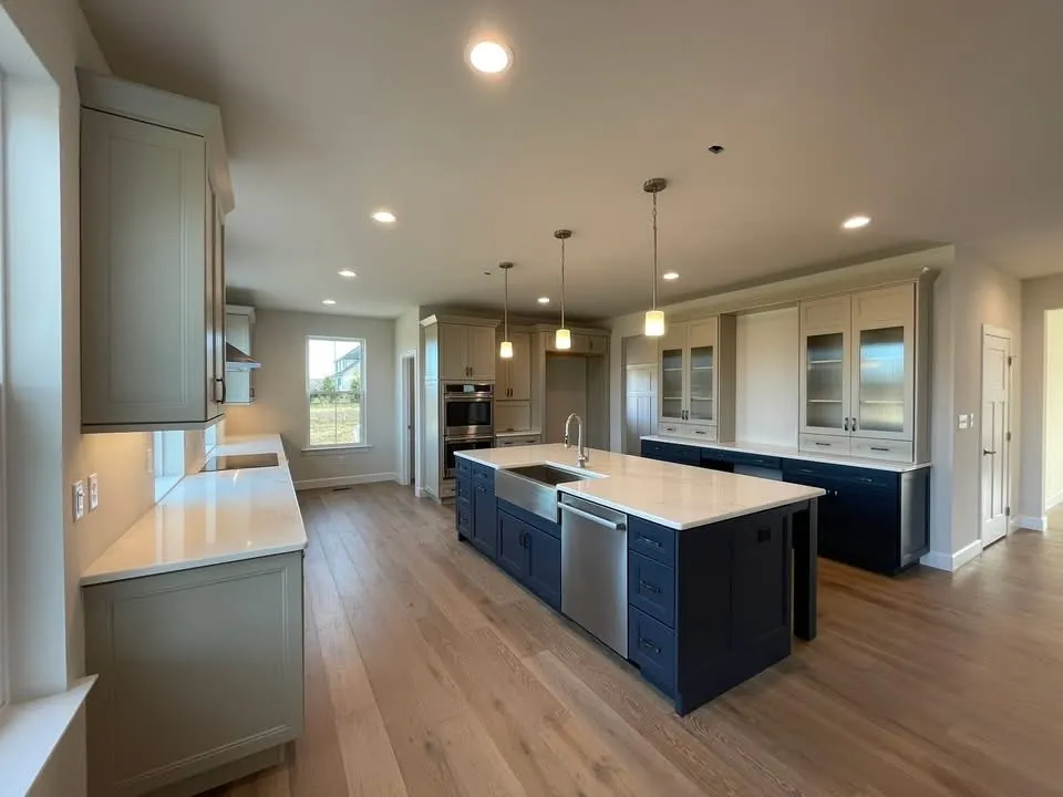 A modern kitchen featuring two-tone cabinetry with a navy island and light grey perimeter cabinets.