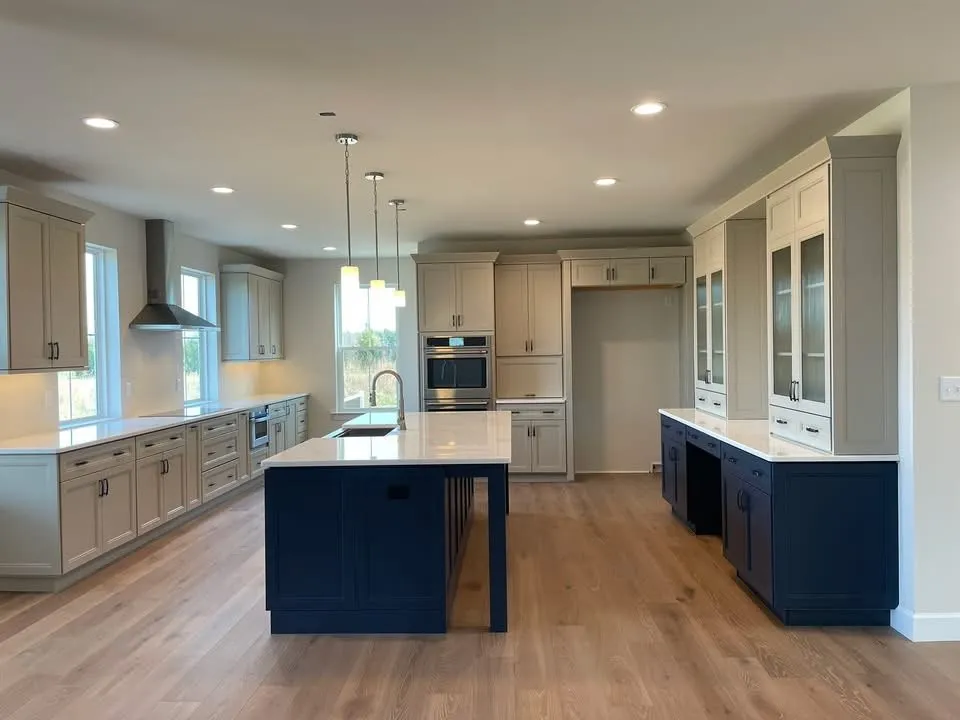 A modern kitchen featuring light gray perimeter cabinets and a contrasting dark navy blue center island.