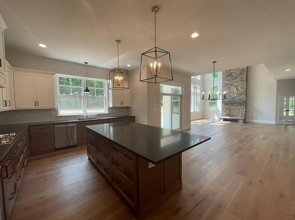 A modern kitchen features white upper cabinets and dark wood lower cabinets with a large island.