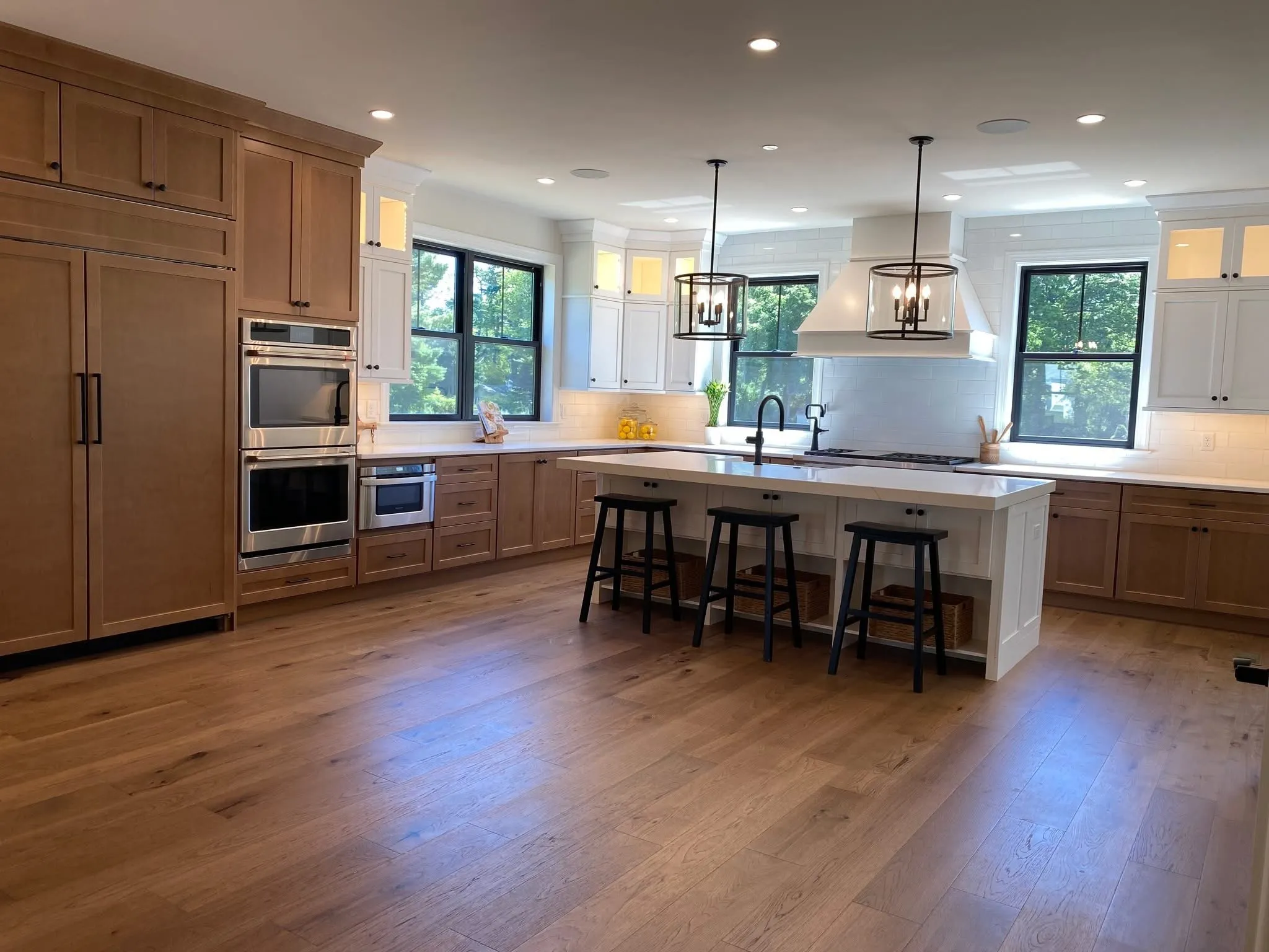 A spacious kitchen featuring natural wood cabinets, white upper cabinets, and a central white island.