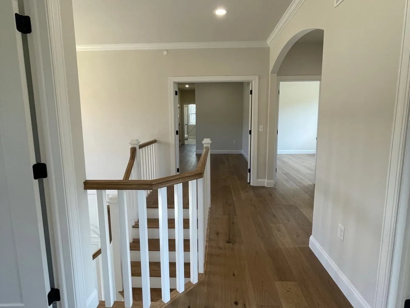 A staircase with white balusters and a natural oak handrail leading to a hallway.