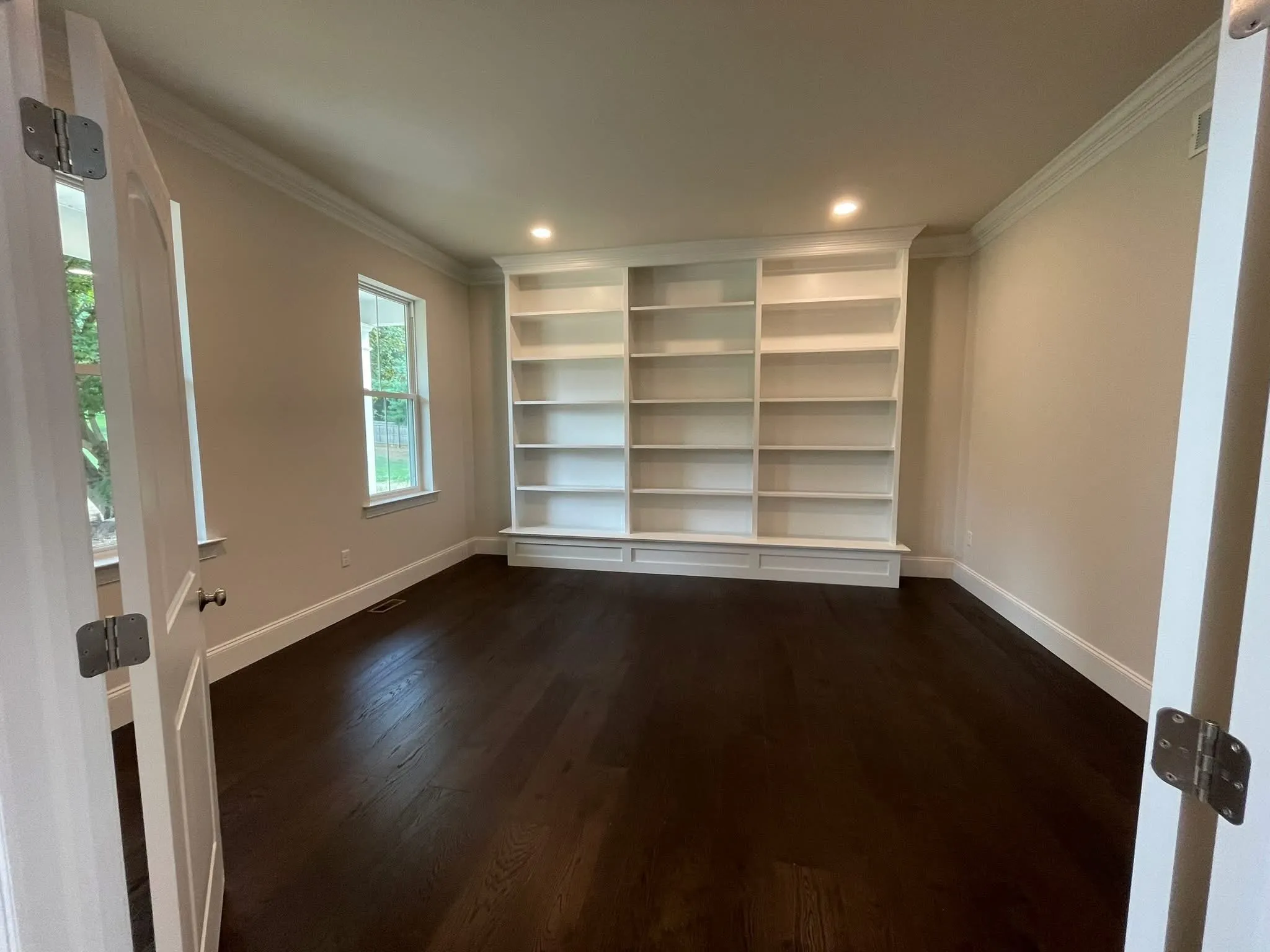 A set of white built-in bookshelves installed against a wall in an empty home office.