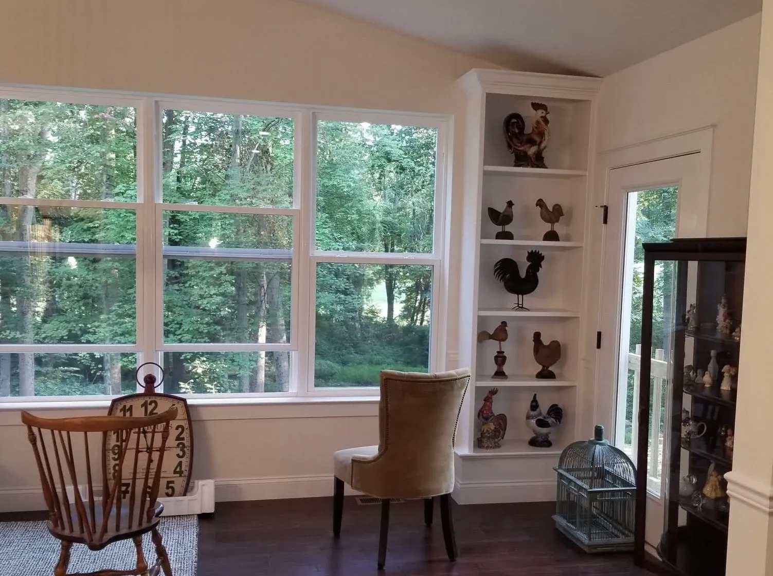 A white built-in bookshelf sits next to a large window in a sunlit room.
