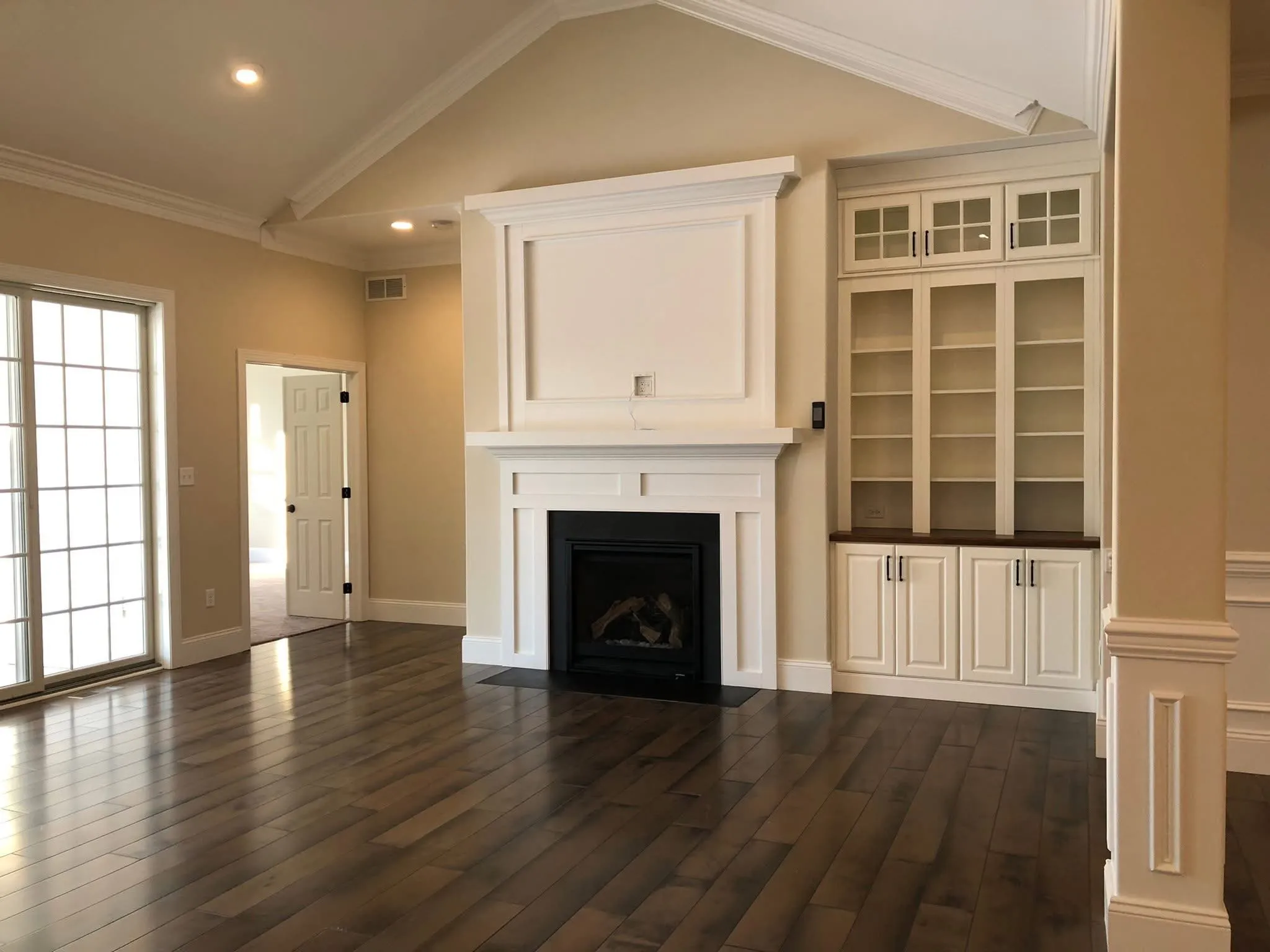 A white fireplace mantel with built-in shelving and cabinets in a room with hardwood floors.
