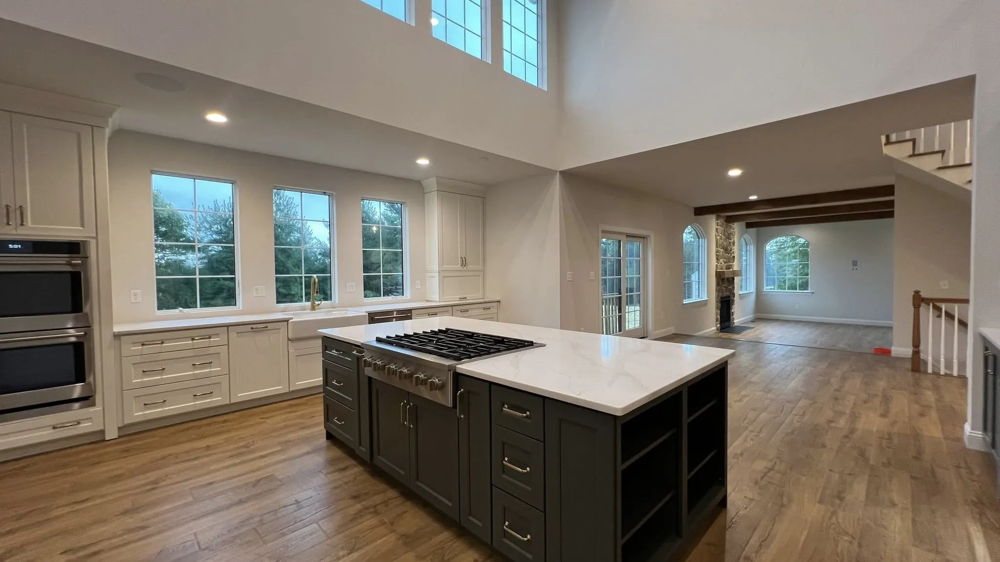 A spacious kitchen features white perimeter cabinets, a large navy blue island, and hardwood flooring.