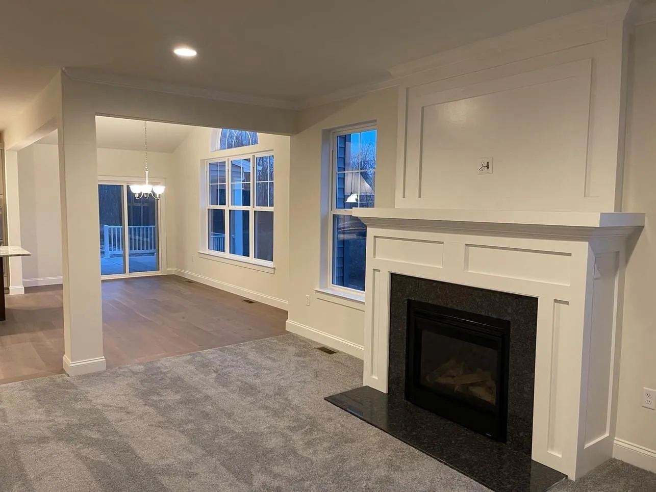 A white wooden fireplace mantel and surround with a black granite hearth in a living room.