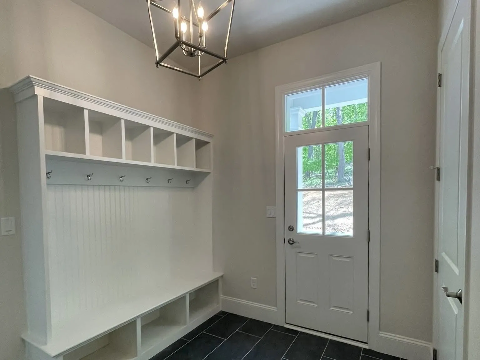 White mudroom lockers with bench seating and cubbies installed against a wall with beadboard backing.