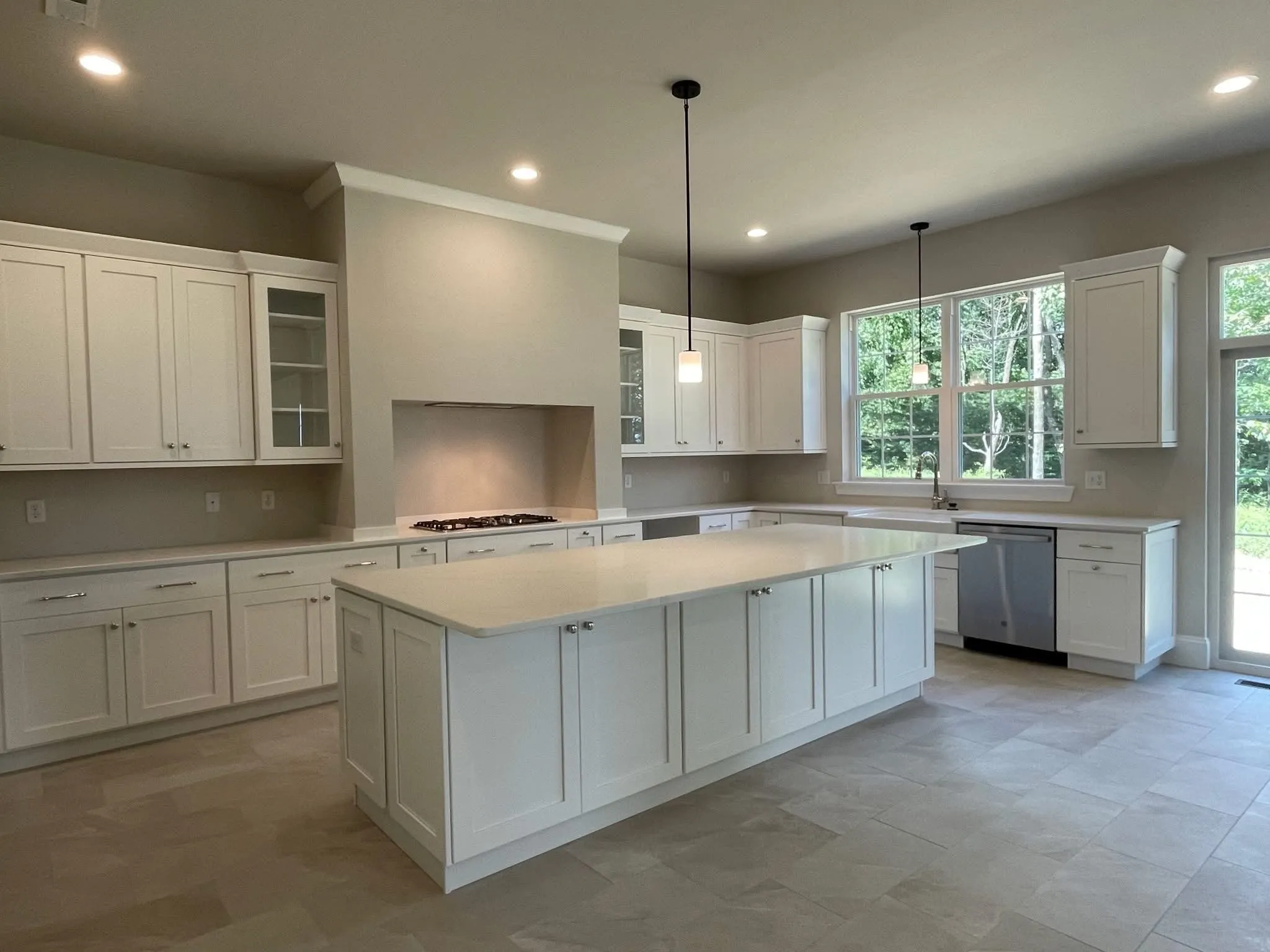 A spacious kitchen featuring white shaker cabinets, a large central island, and a range hood.