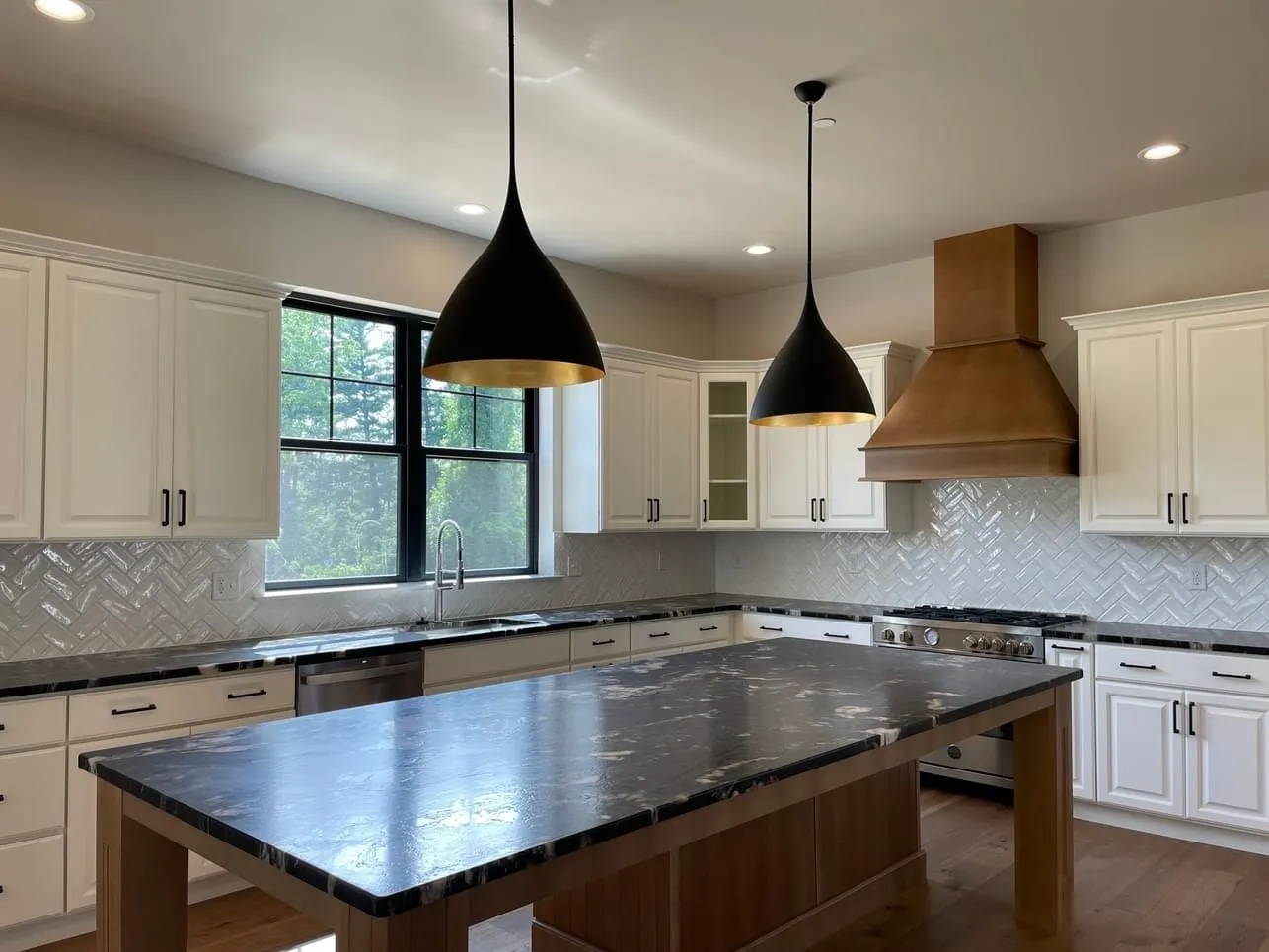 White shaker cabinets and a large wood island with dark stone countertops in a kitchen.