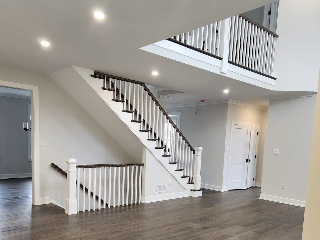 A staircase with white balusters and a dark wood handrail in a two-story residential foyer.